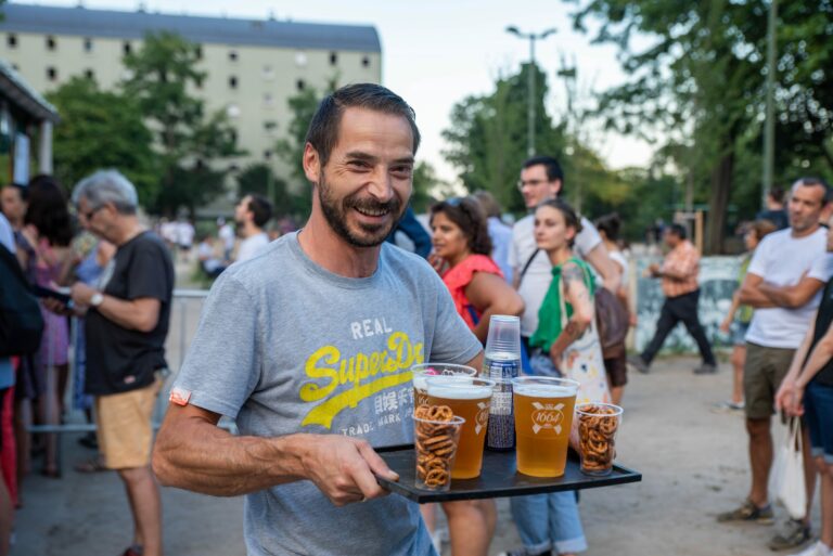 homme souriant porte un plateau avec apéros et boissons